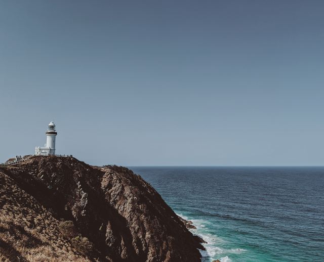 Cape Byron Lighthouse on the headland above the ocean on a clear day.