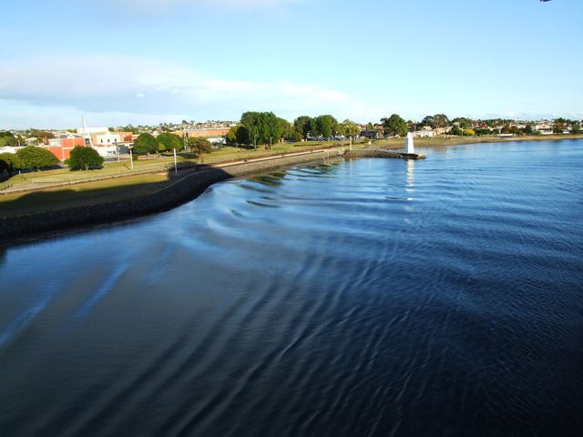 Devonport's Mersey River foreshore and parkland with a small white lighthouse, seen from the water.