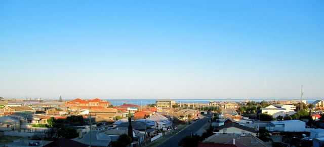 Rooftops of Geraldton stretching to the port and the ocean under a clear blue sky.