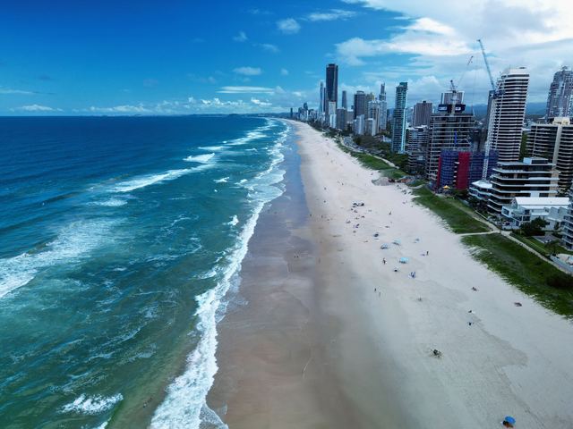 Aerial view of the Gold Coast beachfront with high-rise towers lining the sand towards Surfers Paradise.