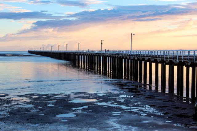 The long Urangan Pier at Hervey Bay stretching out over calm water at sunset.