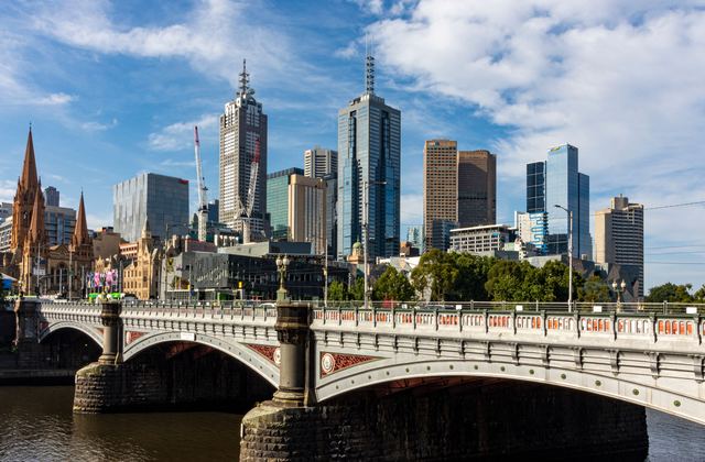 Melbourne city skyline above Princes Bridge and the Yarra River, with St Paul's Cathedral spires.