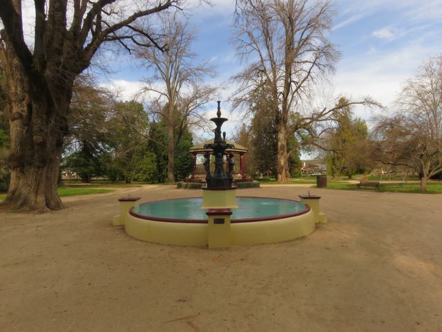 The ornate fountain and red bandstand in Orange's Cook Park, under tall bare winter trees.