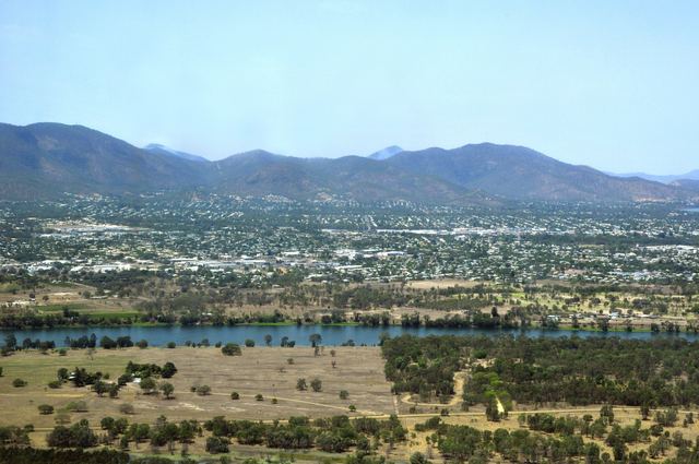 Aerial view of Rockhampton from the west, with the Fitzroy River in front and the Berserker Range behind the city.