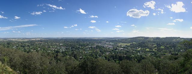 Panorama over Bowral, the main town of the Southern Highlands, nestled in green trees beneath a blue sky.