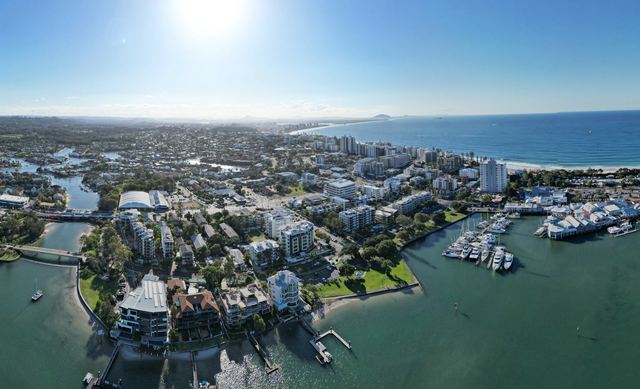 Aerial view of Mooloolaba with the river, marina, beachfront towers and the coastline stretching north.