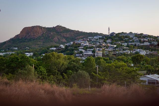 Castle Hill rising above hillside homes in Townsville at dusk.
