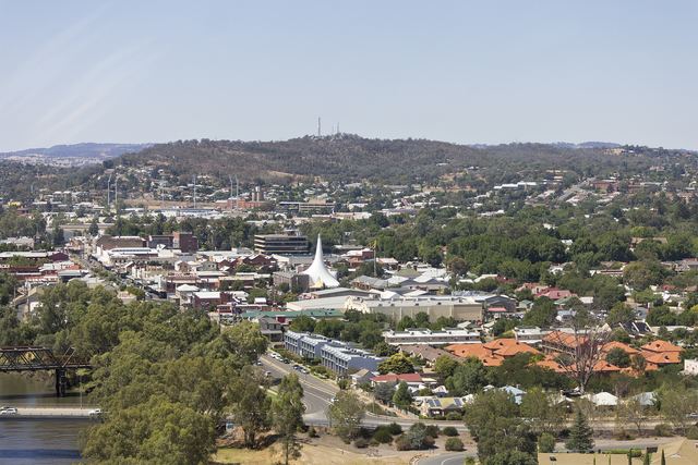 Central Wagga Wagga seen from above the Murrumbidgee River, with the old truss bridge, the white tent-roofed church and Willans Hill behind.