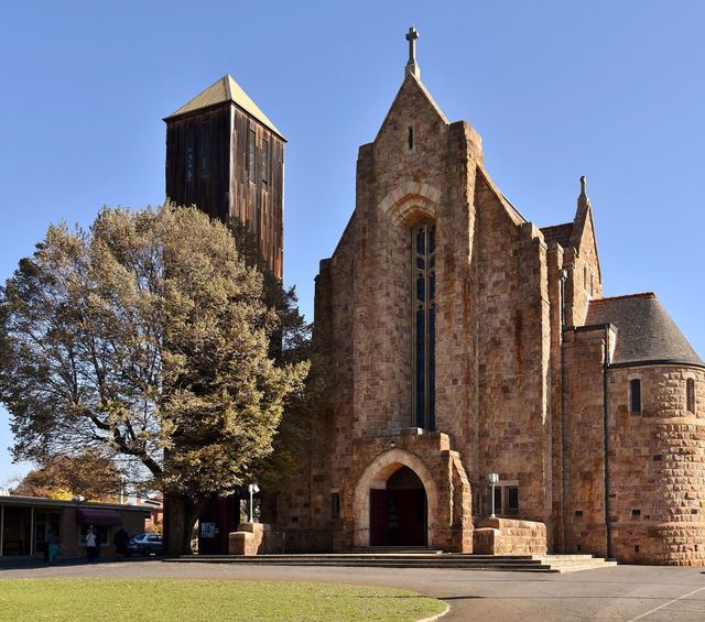 The sandstone Holy Trinity Cathedral in Wangaratta with its timber bell tower, on a clear autumn day.