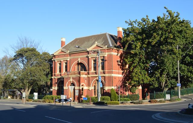 The red-brick Warragul Shire Hall on a quiet street corner on a sunny afternoon.