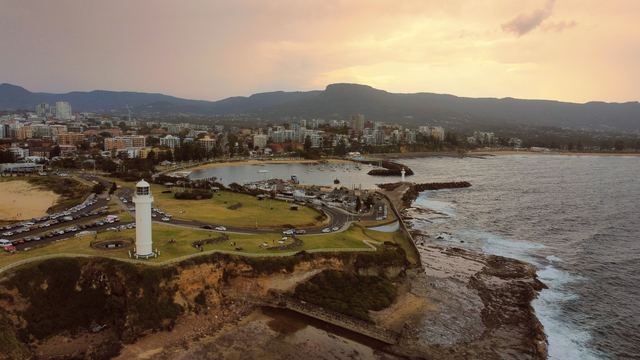 Aerial view of Flagstaff Point lighthouse, Wollongong harbour and the city below the escarpment at dusk.