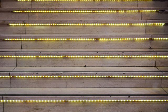Warm LED strip lights set into the front edge of each step on a stone staircase.