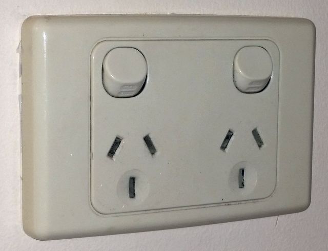 A white Australian double power point with two switches on a painted wall.